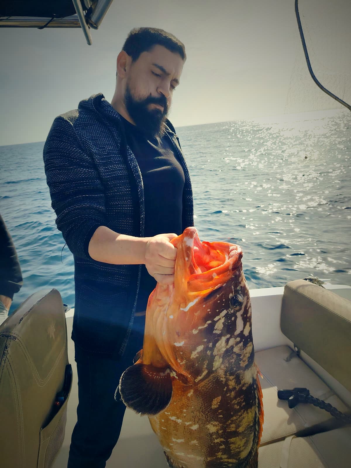 Le même mérou, porté comme un trophée